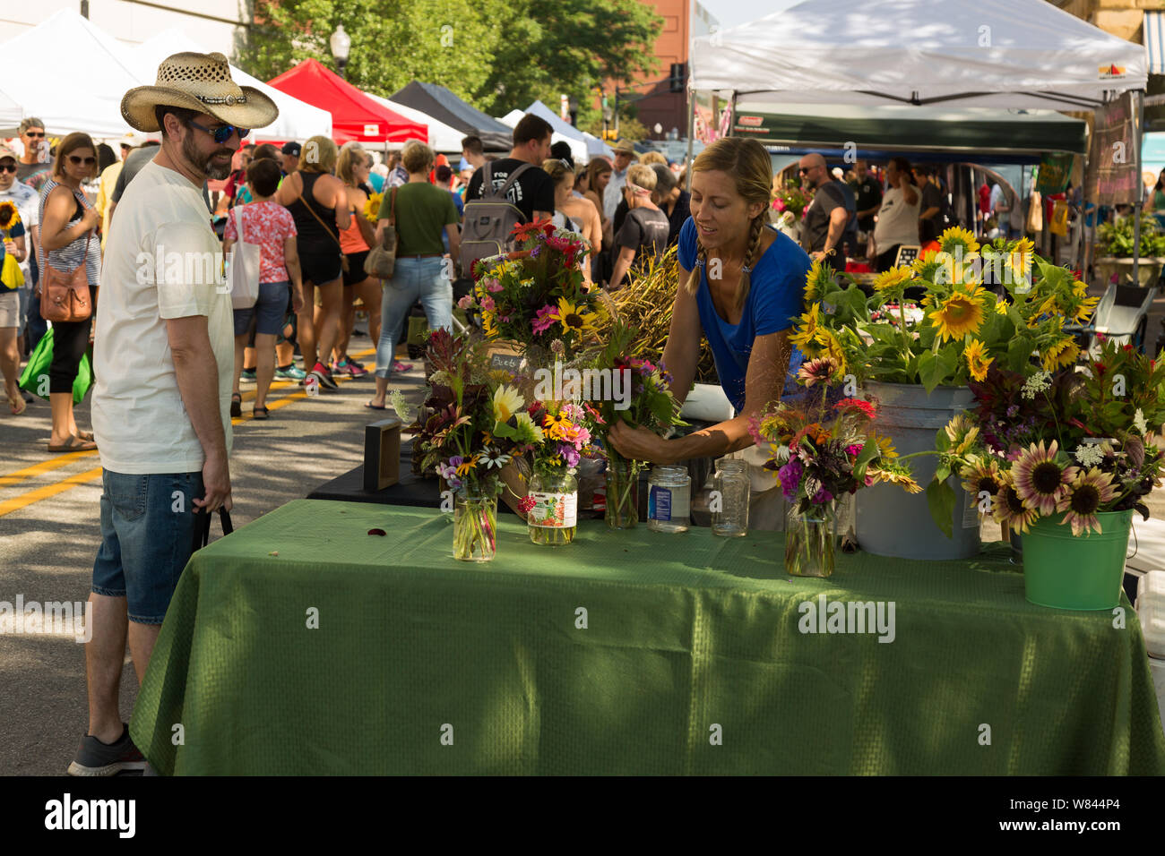 Un fornitore a Fort Wayne il Mercato degli Agricoltori promuove i suoi fiori per un cliente nel centro di Fort Wayne, Indiana, Stati Uniti d'America. Foto Stock