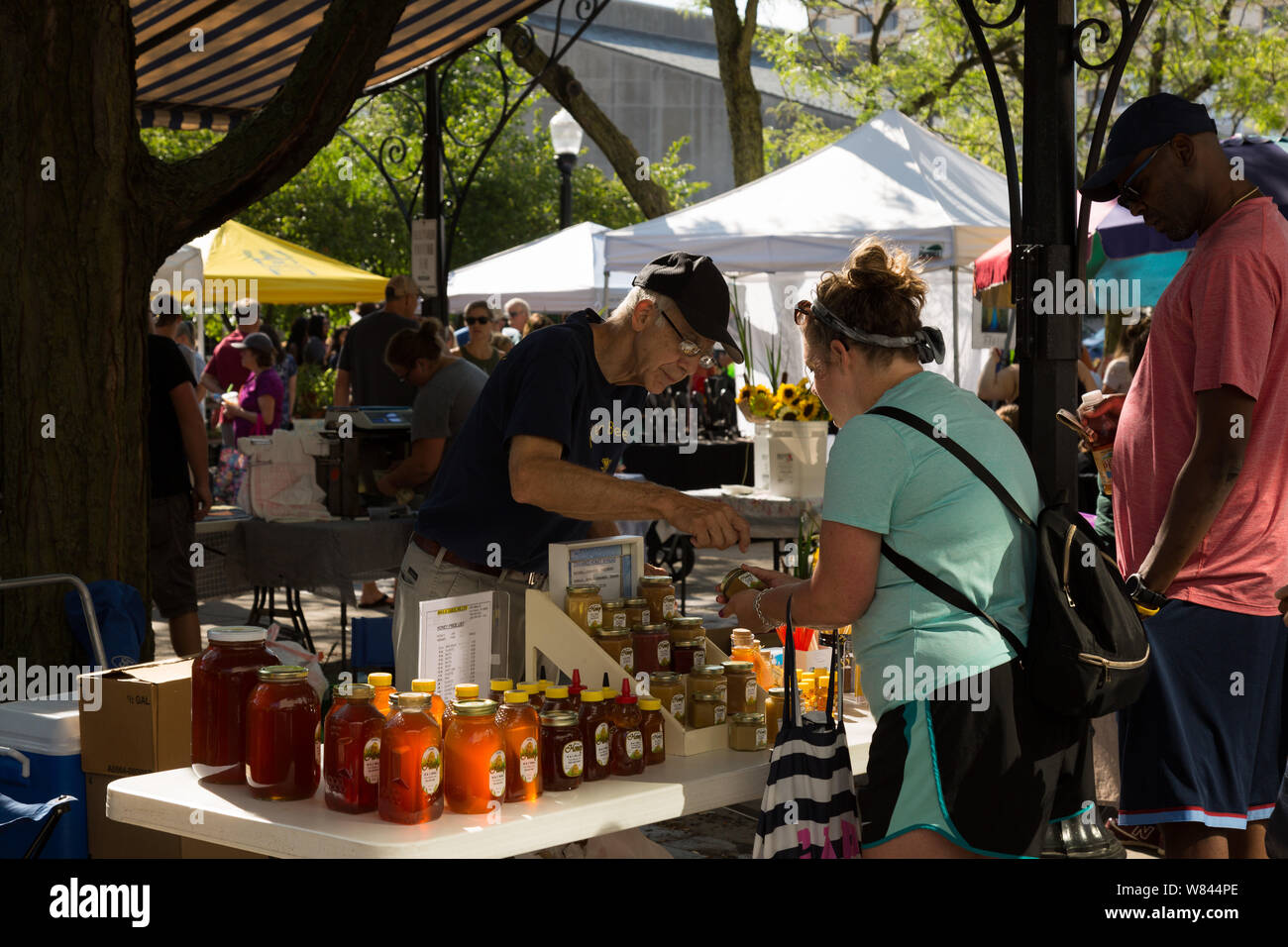 Un venditore al M&C Miele stand a Fort Wayne il Mercato degli Agricoltori effettua una vendita a clienti nel centro di Fort Wayne, Indiana, Stati Uniti d'America. Foto Stock