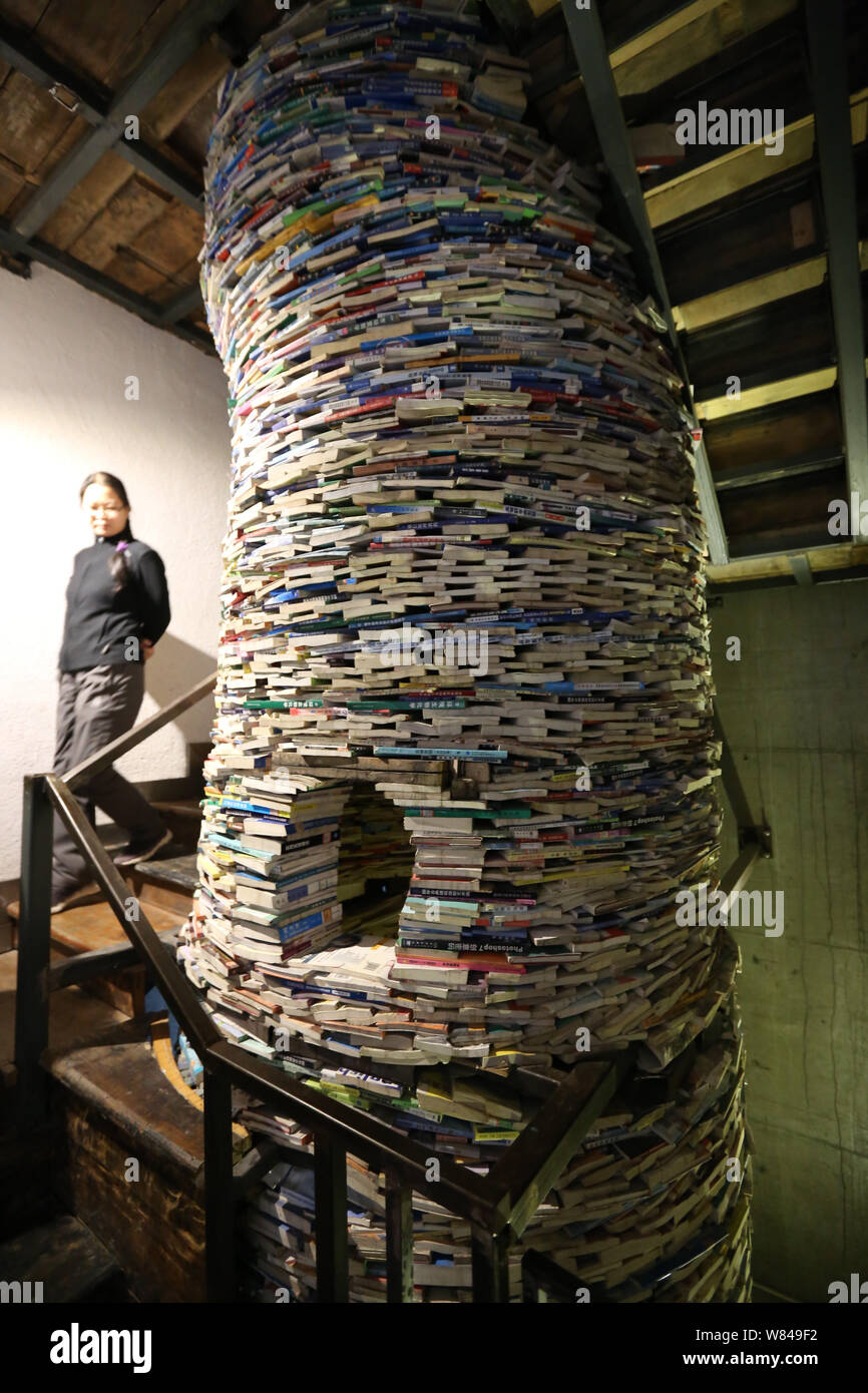 Una donna guarda una ben conformato installazione composta di libri scartati da madre cinese per ricordare la figlia di mai la lettura di libri meccanicamente a Foto Stock