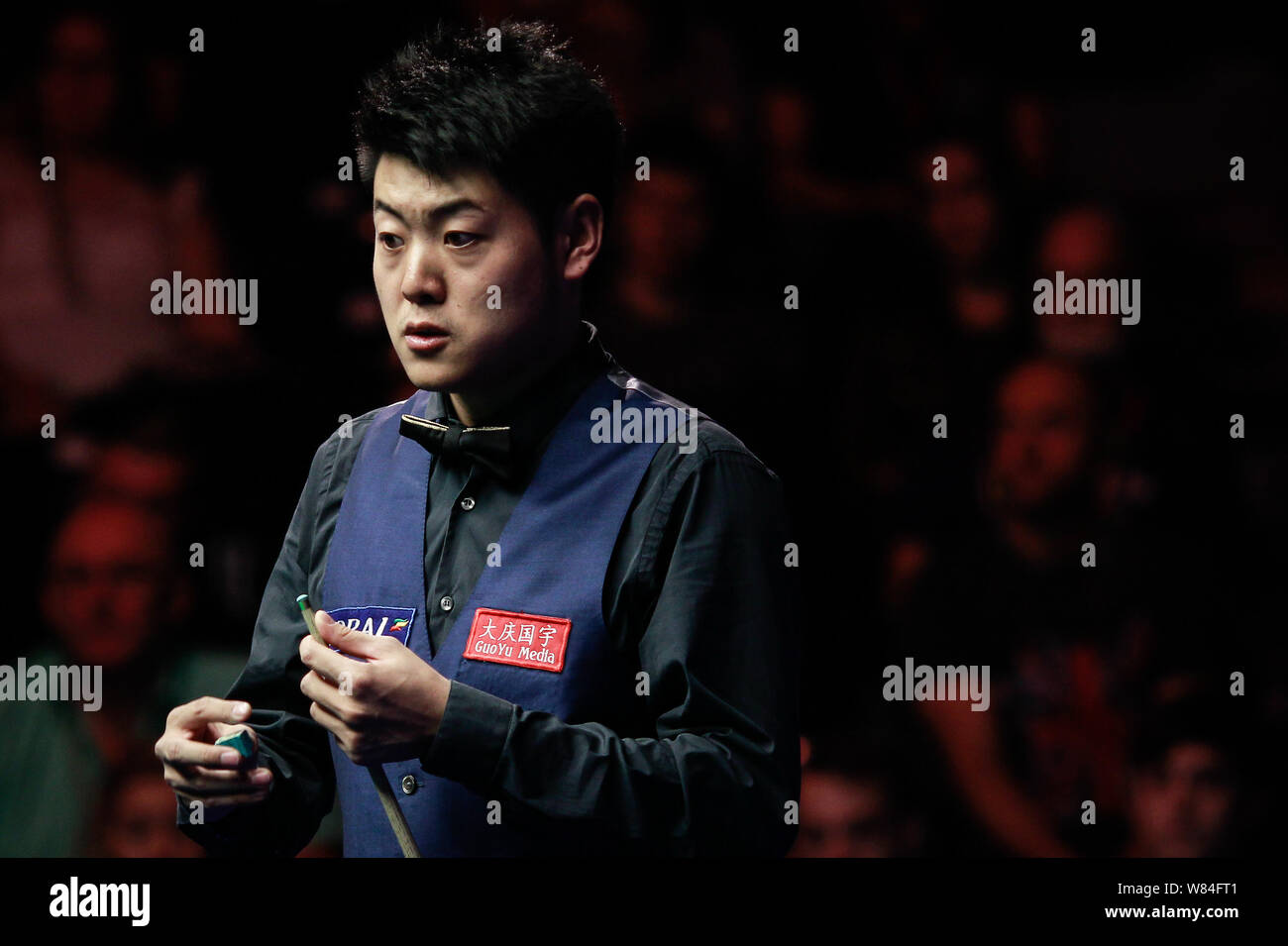 Liang Wenbo della Cina i gessi spunto come egli ritiene che un colpo contro Judd Trump di Inghilterra in loro corrispondenza finale durante l'inglese Open 2016 snooker tou Foto Stock