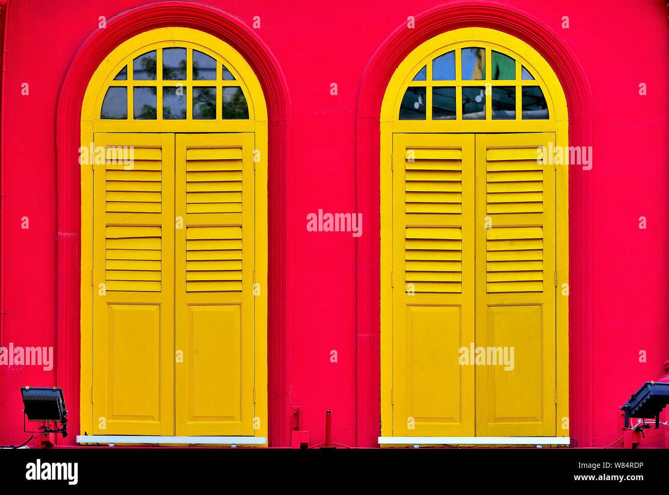 Close up vintage di finestre ad arco con giallo antico persiane di legno rosso sulla parete esterna della tradizionale bottega di Singapore nella storica Chinatown Foto Stock