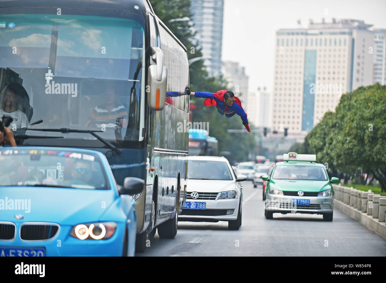 Mago cinese Zhou Jieming vestito come Superman esegue uno spettacolo di magia, far levitare in aria toccando un bus in movimento, in Luoyang city central ch Foto Stock