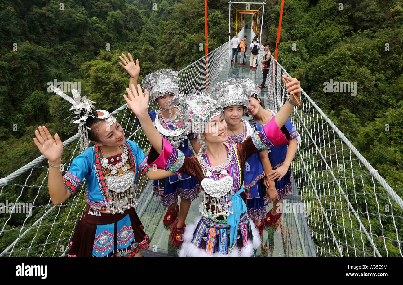 Le donne cinesi di Miao minoranze etniche pongono sul vetro-ponte inferiore in Shuanglonggou foresta vergine resort in Rongshui Miao contea autonoma, così Foto Stock