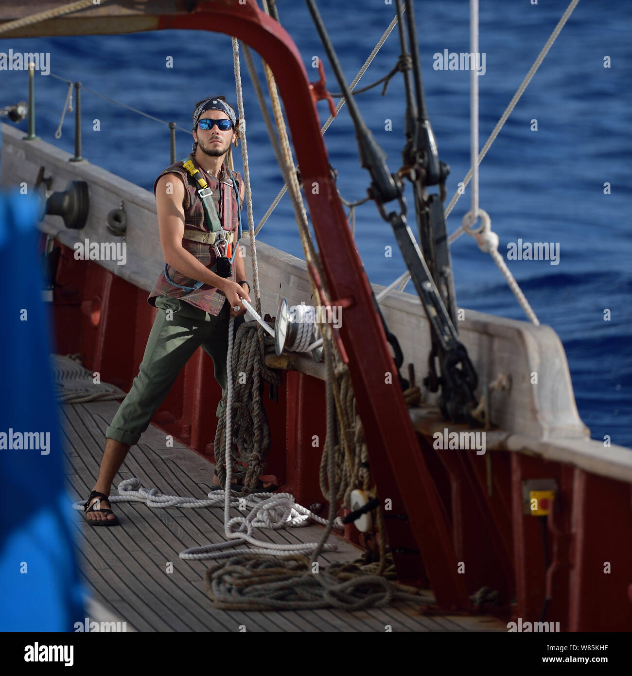 L'uomo la rifinitura della vela a bordo, Corwith Cramer, un 134-piede brigantino in acciaio costruito come una nave di ricerca. Sargasso Sea, Bermuda, aprile 2014. Foto Stock
