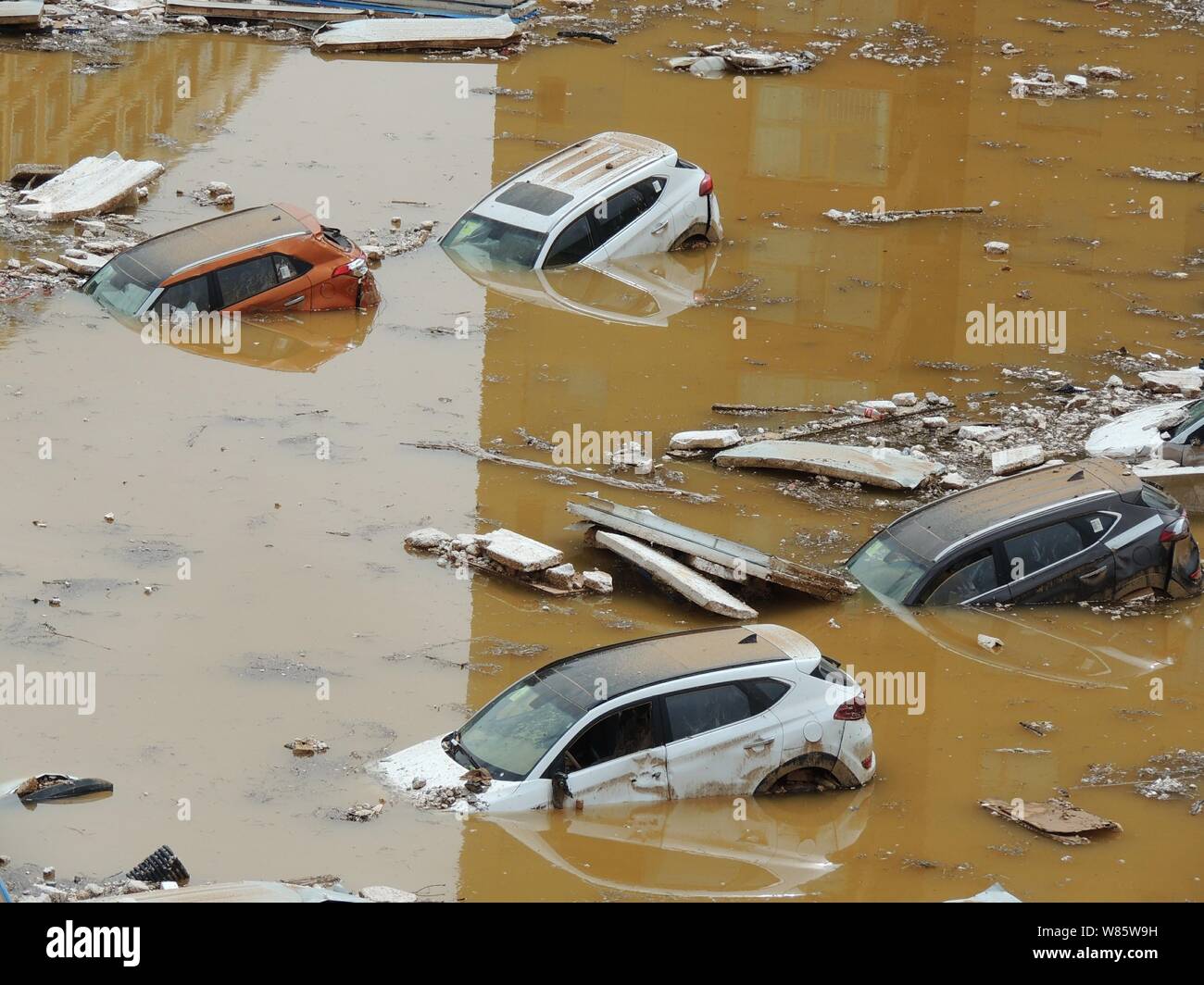 Le automobili private sono immerse in acqua dopo essere stata lavata da inondazioni causate da un acquazzone in una buca dal parcheggio in un quartiere residenziale in Foto Stock