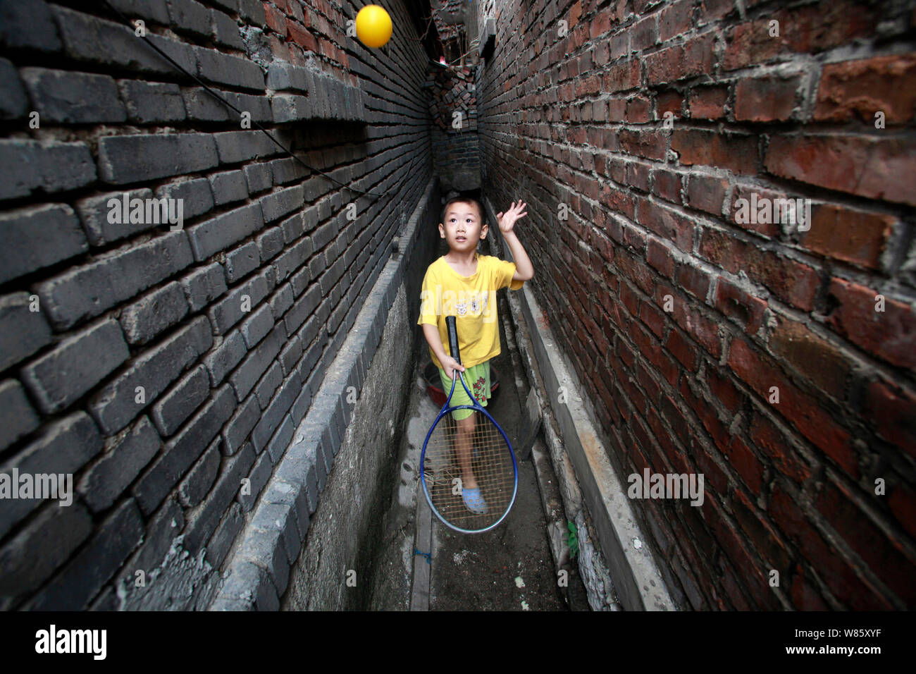 Sette-anno-vecchio ragazzo Shun Shun gioca con una palla di ping-pong con una racchetta da tennis in uno stretto vicolo in un hutong in Ji'nan city, est della Cina di Shandong Foto Stock