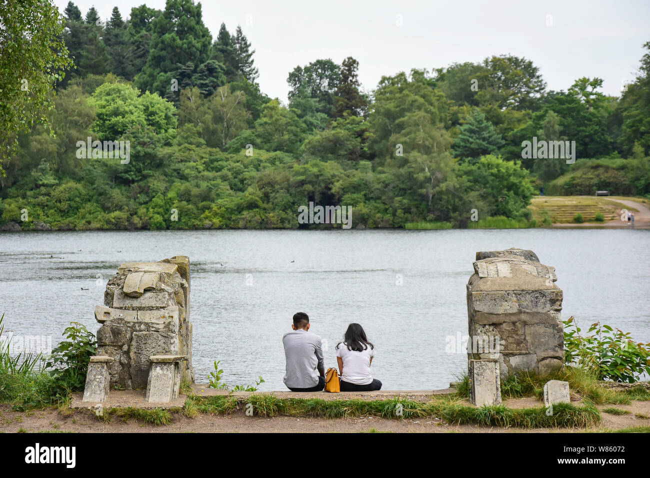 Giovane seduto sulla riva di Virginia Water Lake, Windsor Great Park, Runnymede, Surrey, England, Regno Unito Foto Stock