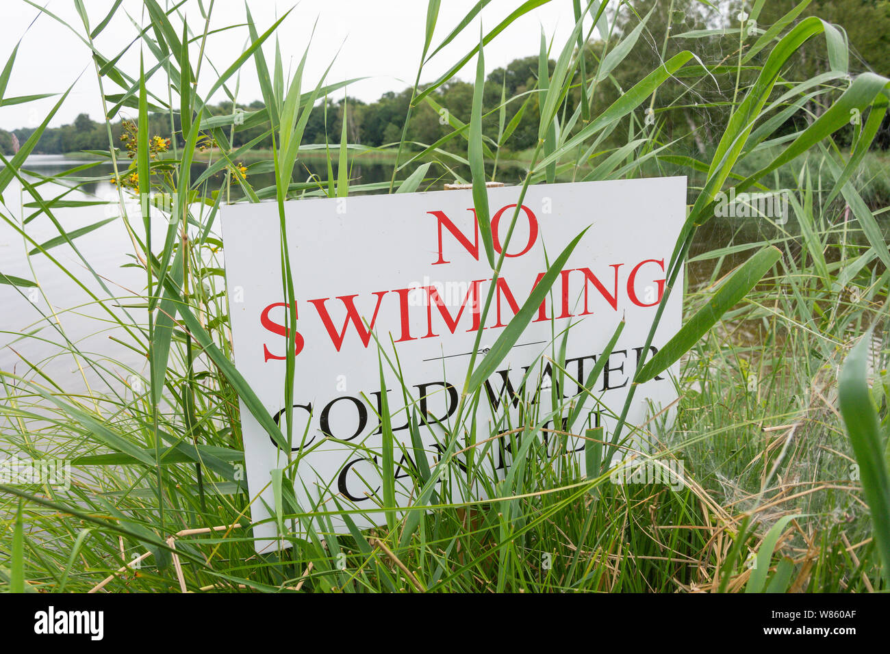 'No nuoto, acqua fredda può uccidere" segno da riva di Virginia Water Lake in estate, Windsor Great Park, Runnymede, Surrey, England, Regno Unito Foto Stock