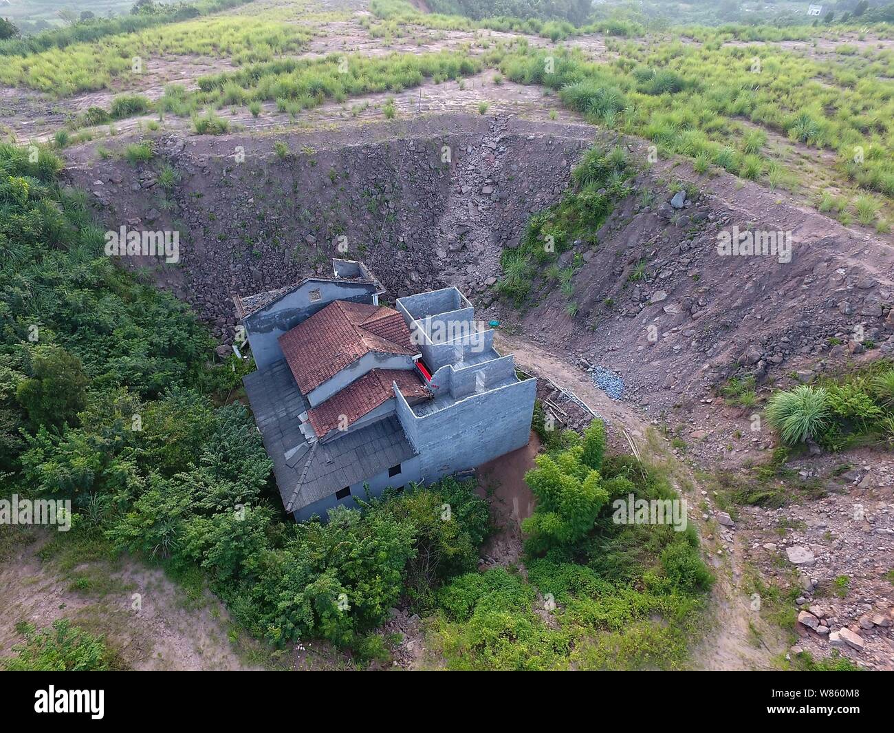 Un chiodo casa il cui proprietario ha rifiutato di spostare a causa di dispute sui dettagli di compensazione è isolato in una fossa presso il cantiere per la costruzione di un settore industriale Foto Stock