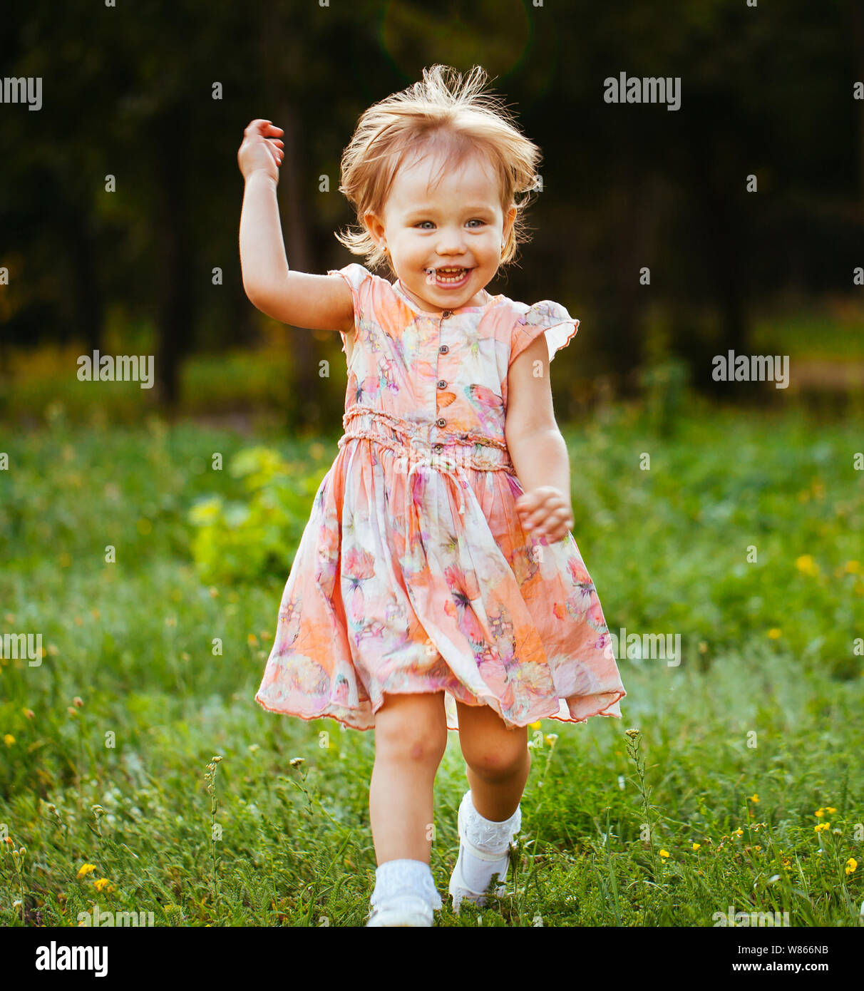 Felice carino bambina in esecuzione sull'erba nel parco. La felicità. Foto Stock