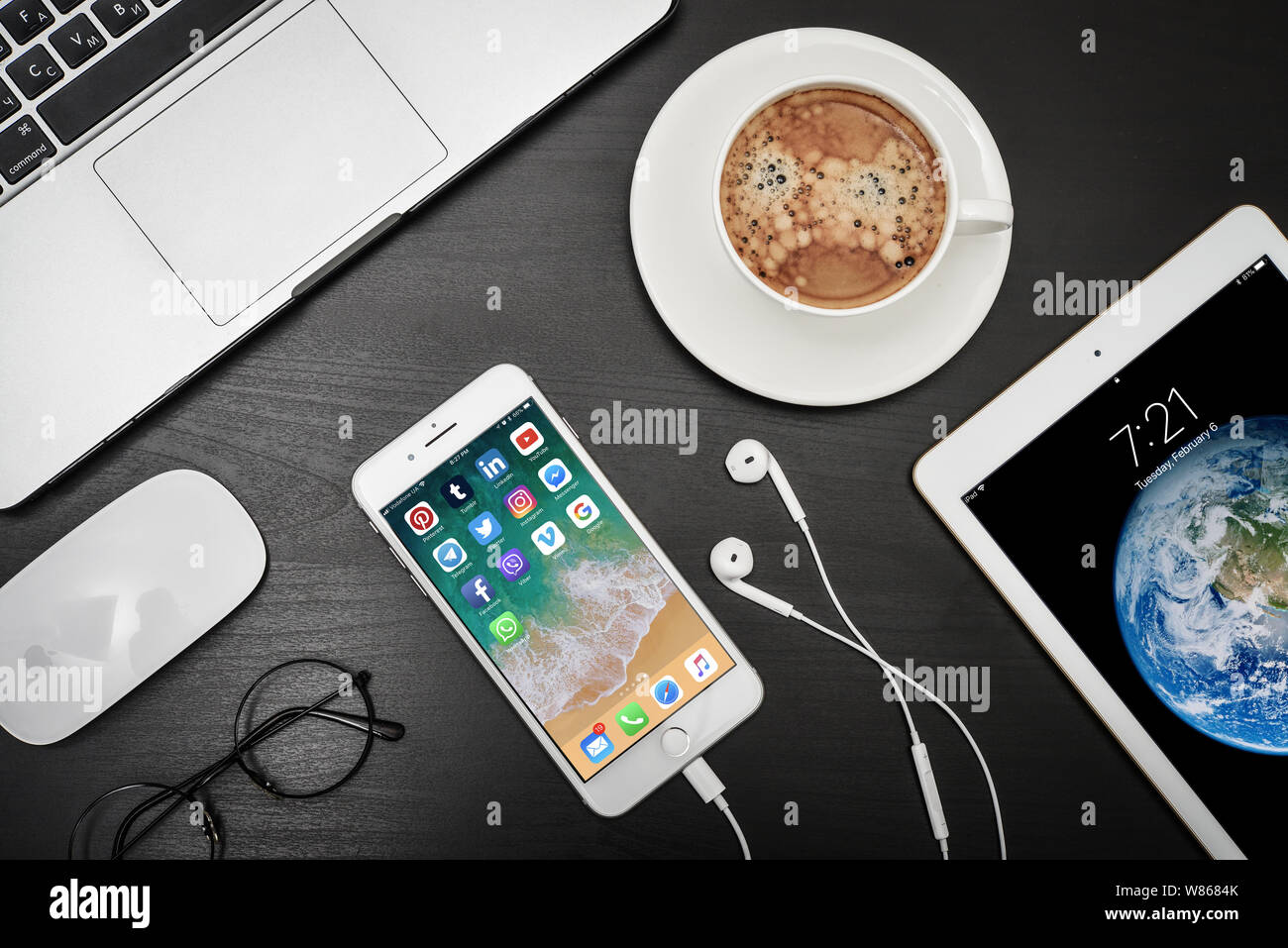 Kiev, Ucraina - Fabruary 6, 2018: Apple iPhone 8 plus con social network app sullo schermo con macbook e ipad, il caffè e le cuffie sulla scrivania nera, Foto Stock