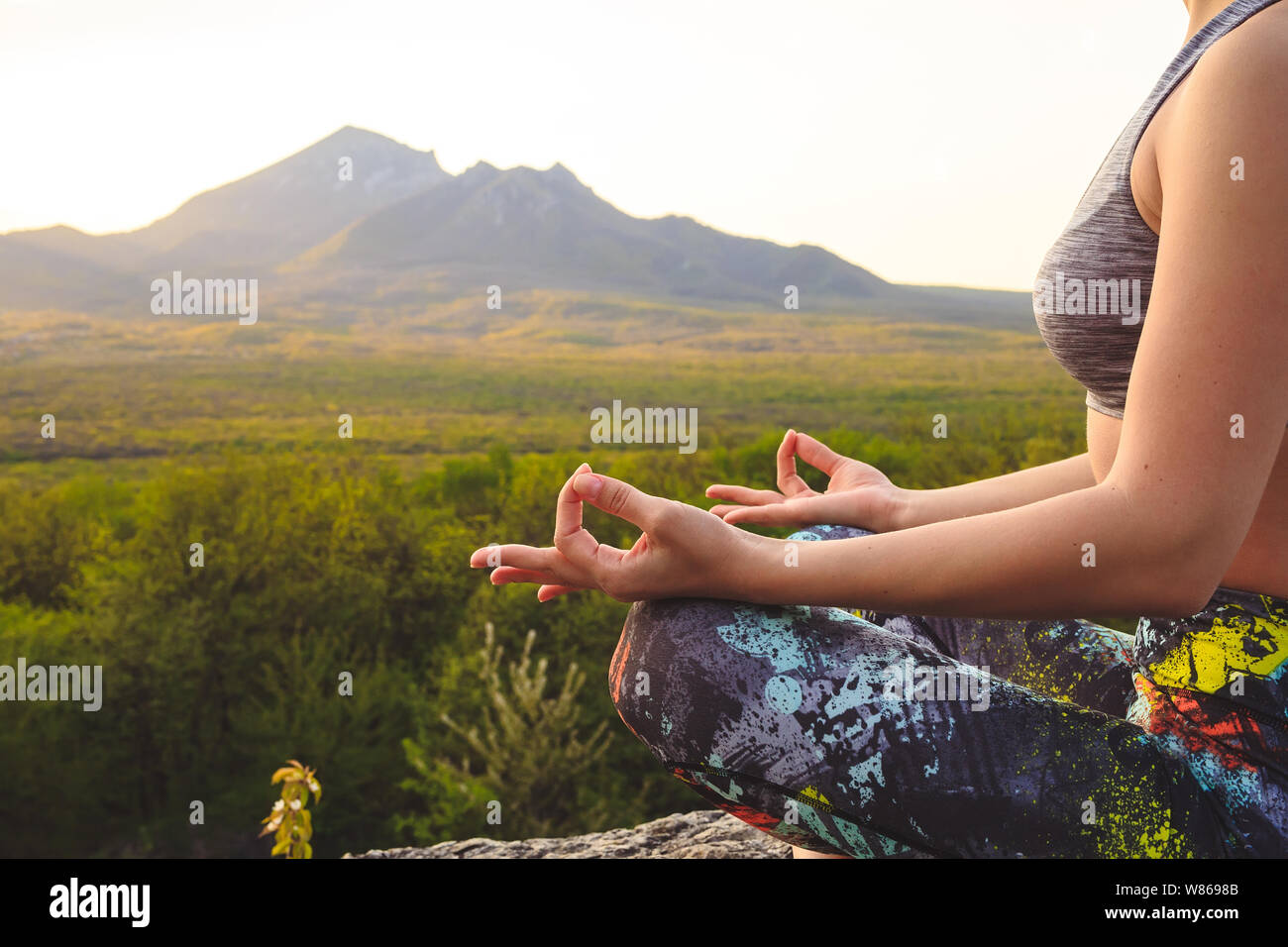 Giovane donna a praticare yoga o pilates al tramonto o l'alba nella splendida località di montagna. Foto Stock
