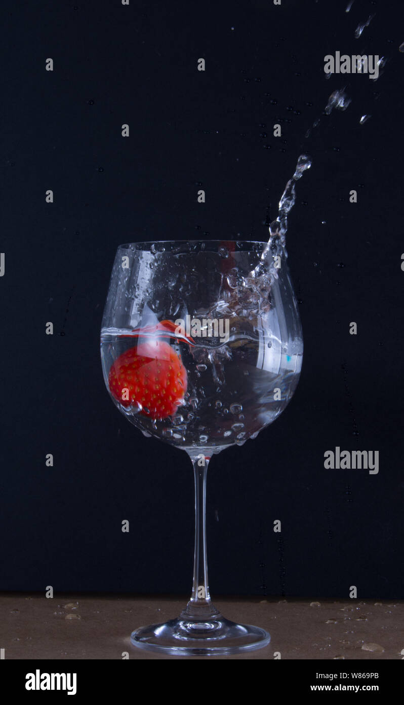 Spruzzi di fragole in un bicchiere con acqua Foto Stock