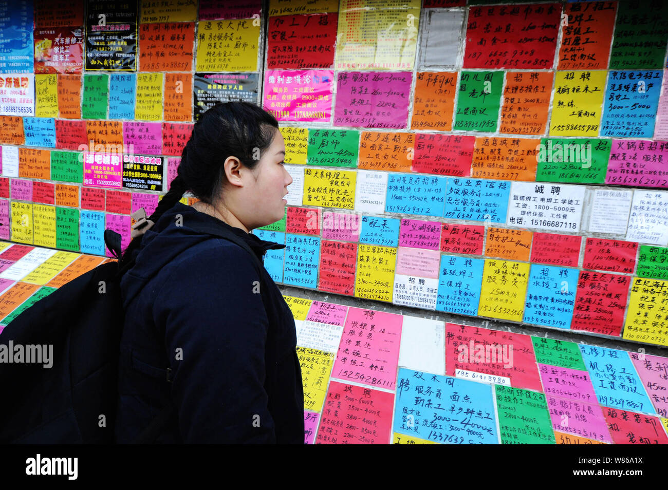 --FILE--un cinese job seeker legge informazioni di assunzione in un mercato del lavoro nella città di Qingdao, Cina orientale della provincia di Shandong, 24 febbraio 2016. Della Cina di urban Foto Stock