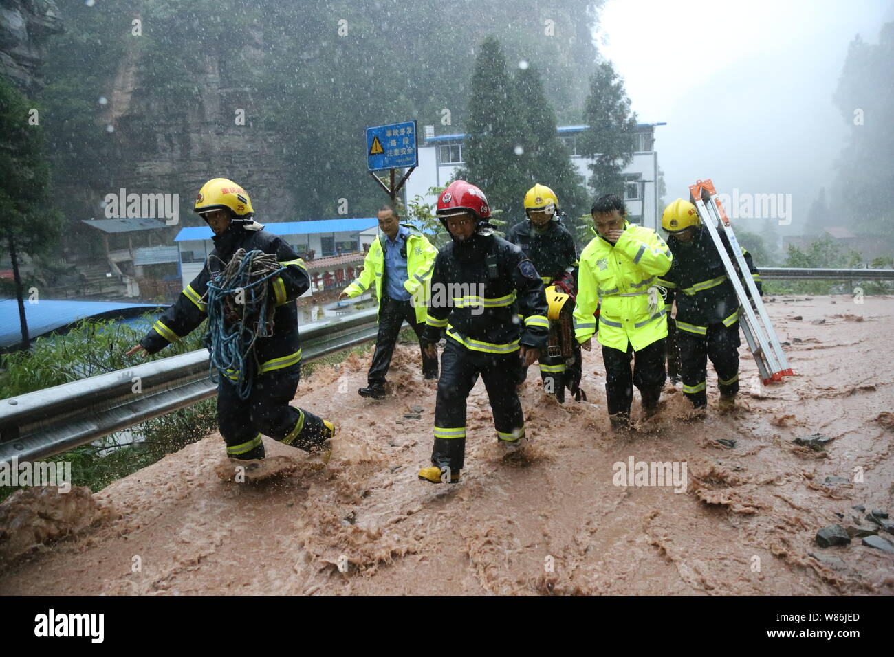 I vigili del fuoco e agenti di polizia giungono per il soccorso di persone in un minibus intrappolato dalle inondazioni causate dalle forti piogge a Chongqing Cina, 19 luglio 2016. A l Foto Stock