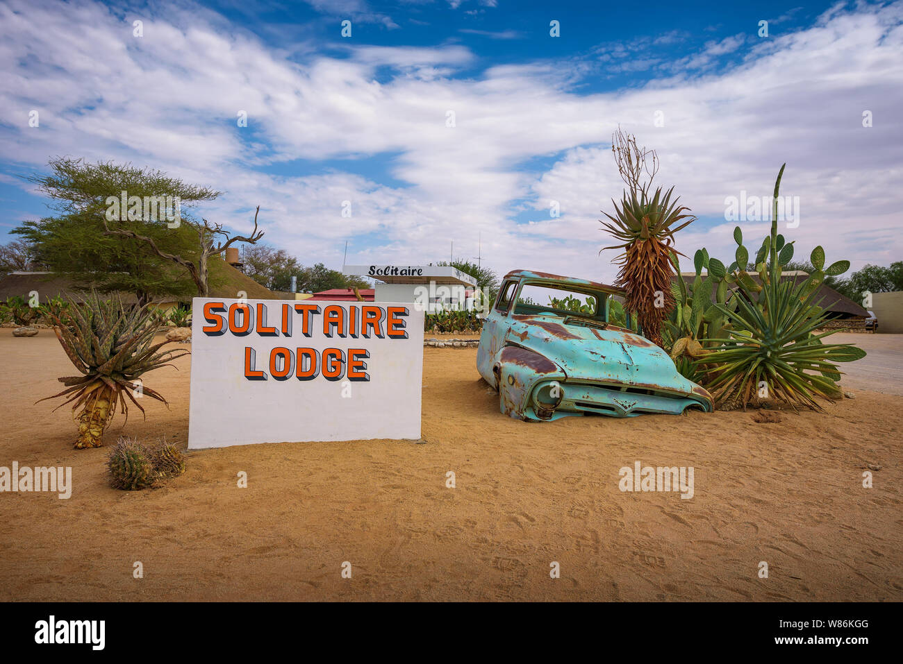 Segno di benvenuto al Solitaire Lodge con un auto rottamata nel Deserto Namibiano Foto Stock