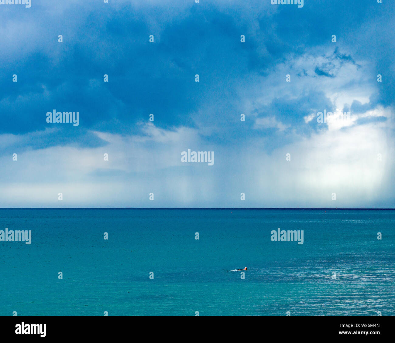 Trieste, Italia, 8 Agosto 2019 - Un lone anziani nuotatore non sembra alla mente la tempesta imminente che incombe sul Mare Adriatico . Credito: Enrique Shore Foto Stock