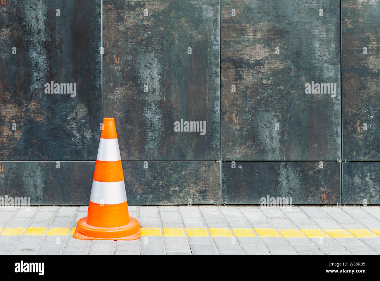 Il traffico di plastica cono contro parete grunge con copia spazio, cono stradale e bollard in piedi sul marciapiede Foto Stock