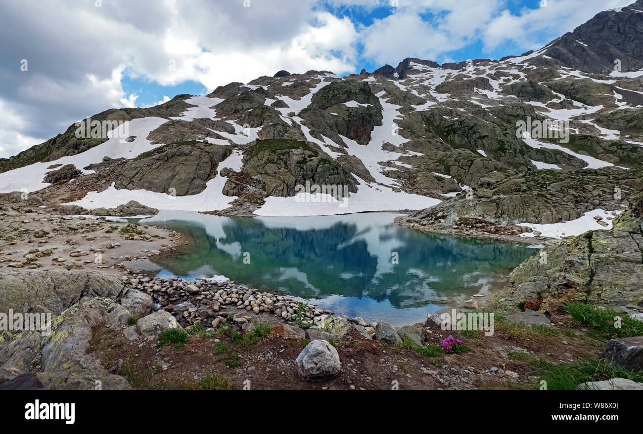 Bellissimo lago di alta montagna nelle Alpi Francesi con acqua turchese e coperte di neve in alcuni luoghi Foto Stock