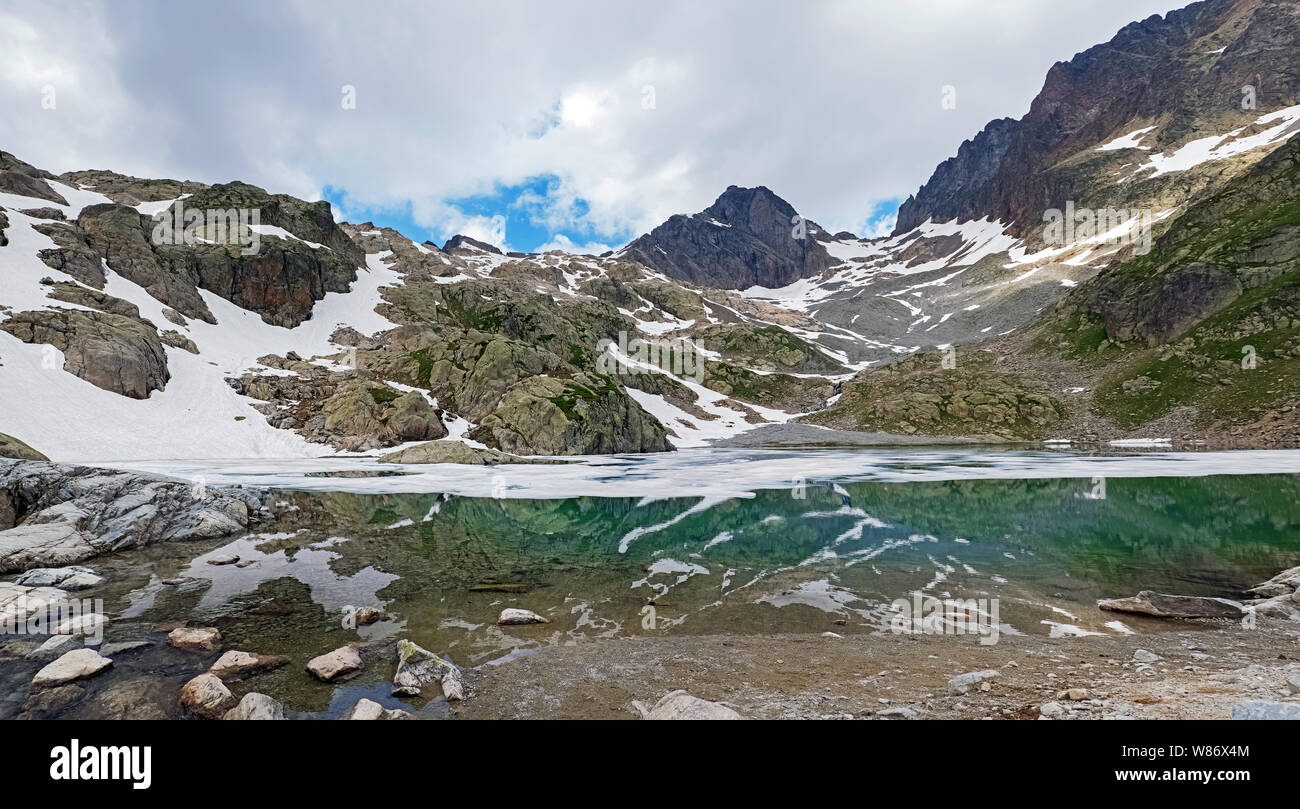 Bellissimo lago di alta montagna nelle Alpi Francesi con acqua turchese e coperte di neve in alcuni luoghi. Lac Blanc panorama Foto Stock