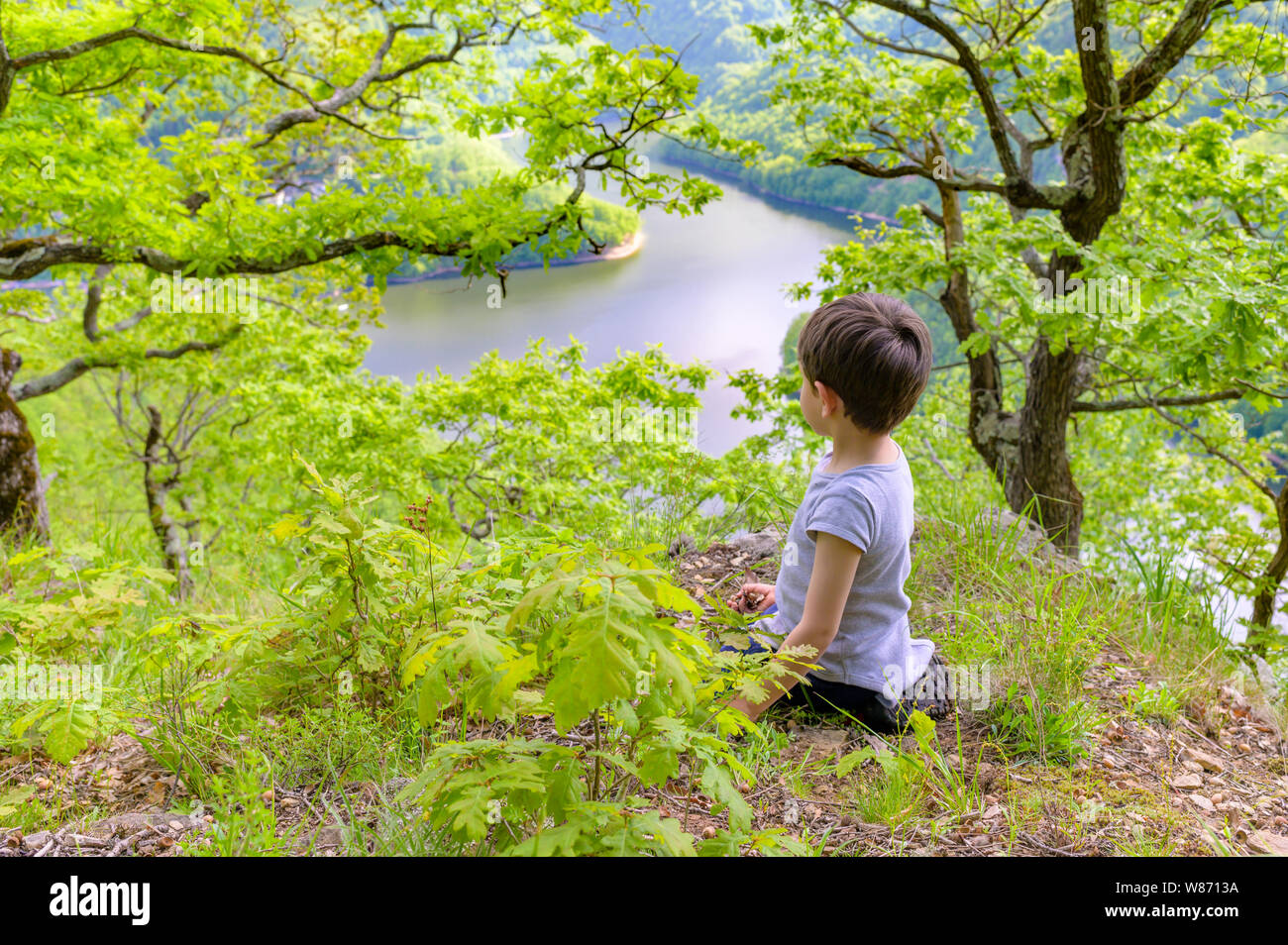 Carino kid giochi da solo nella foresta a lago, giorno di estate Foto Stock