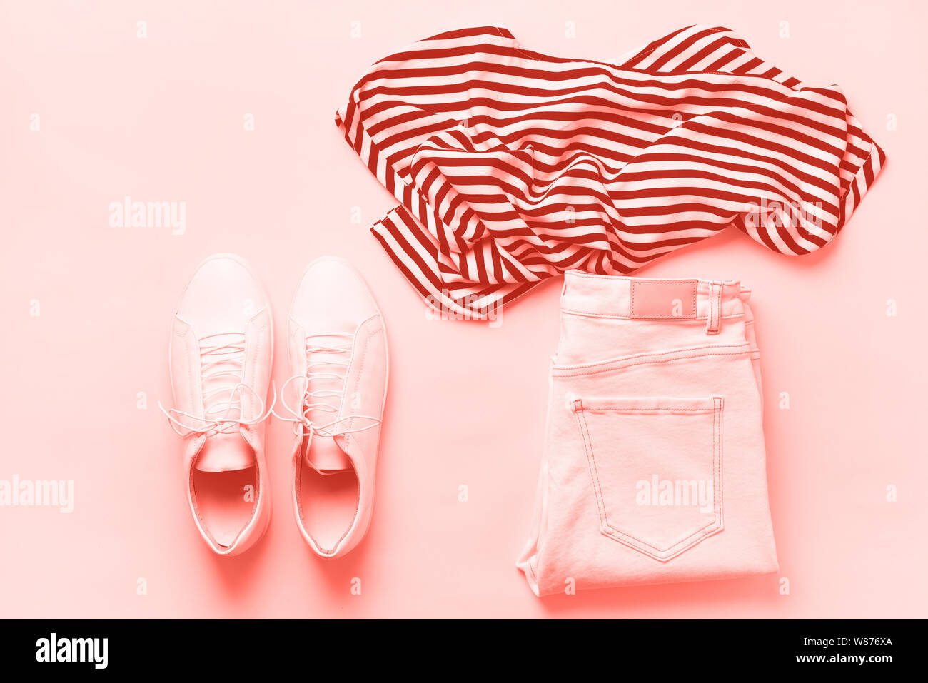 Femmina bianca sneakers e jeans, striped t-shirt su corallo trendy colore di sfondo con una copia dello spazio. Vista dall'alto. Moda estate, capsula guardaroba concetto. Foto Stock