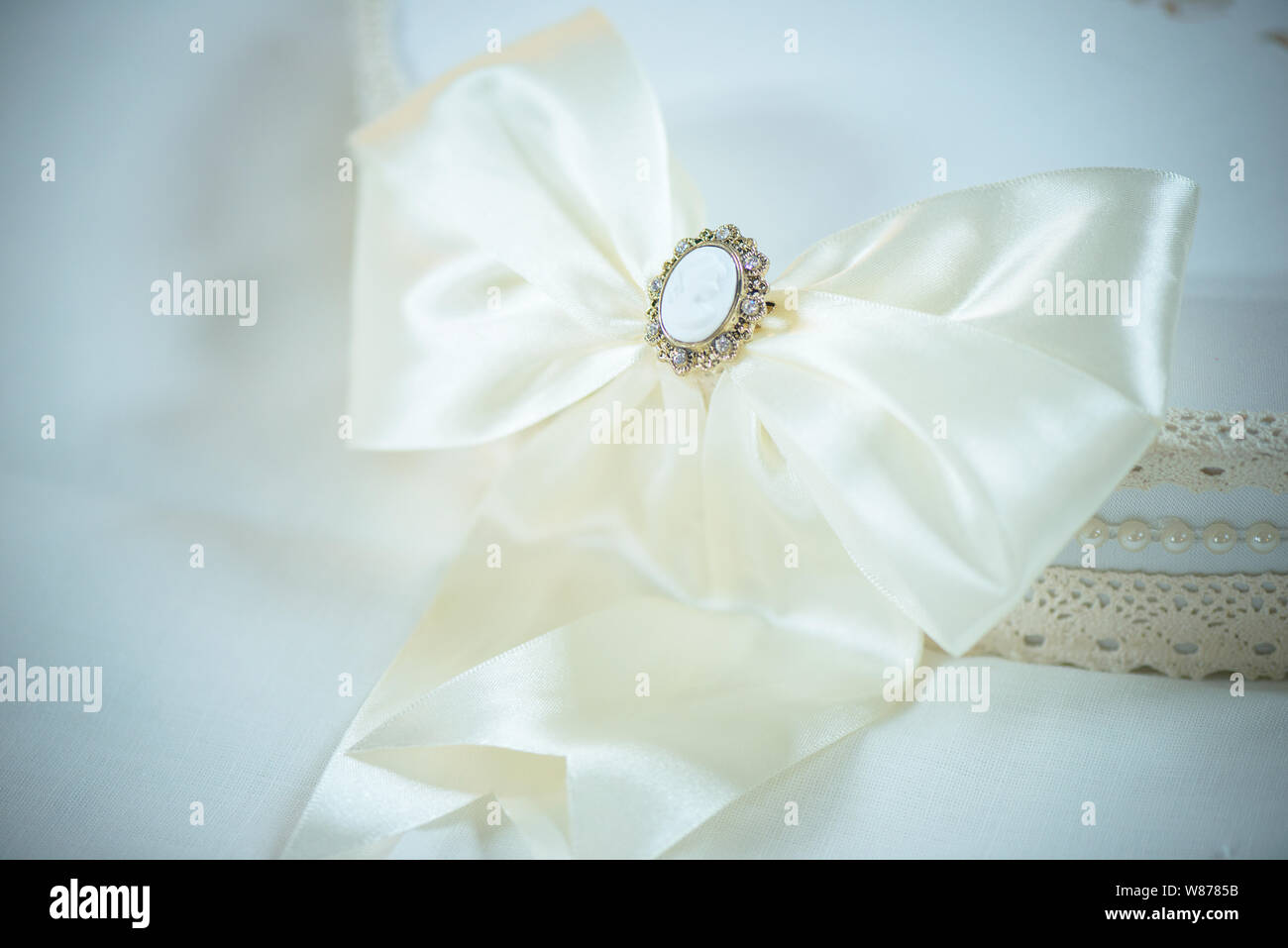 Large White silly nastro con un delicato cammeo spilla a copertura di un bianco estate boemo hat, vintage accessorio per una occasione speciale Foto Stock