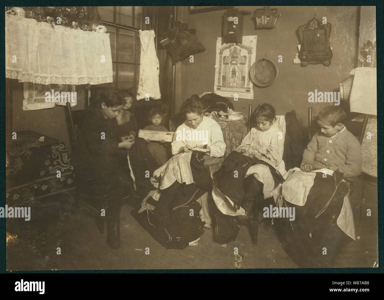 1 P.M. Famiglia di Onofrio Cottone, 7 pl Extra., N.Y., finitura indumenti in un terribilmente malandato tenement. Il padre lavora sulla strada. I tre più antichi i bambini aiutano la madre su capi di abbigliamento. Giuseppe, 14, Andrew, 10, Rosie, 7, e tutti insieme fanno circa 2 dollari a settimana quando il lavoro è abbondante. Ci sono due bambini. Foto Stock