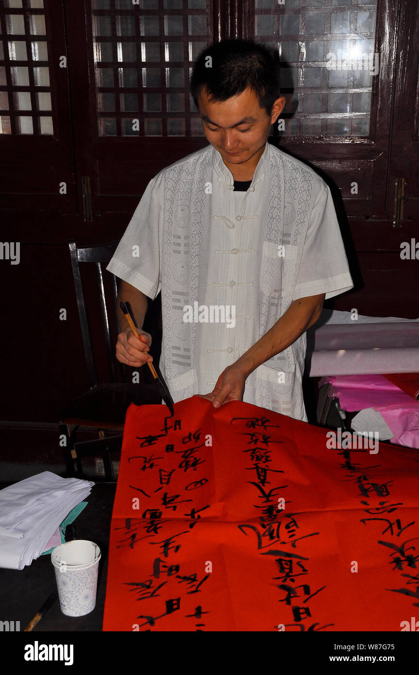Un uomo cinese dimostra la scrittura dei caratteri cinesi in un tempio di Nantong, Cina Foto Stock