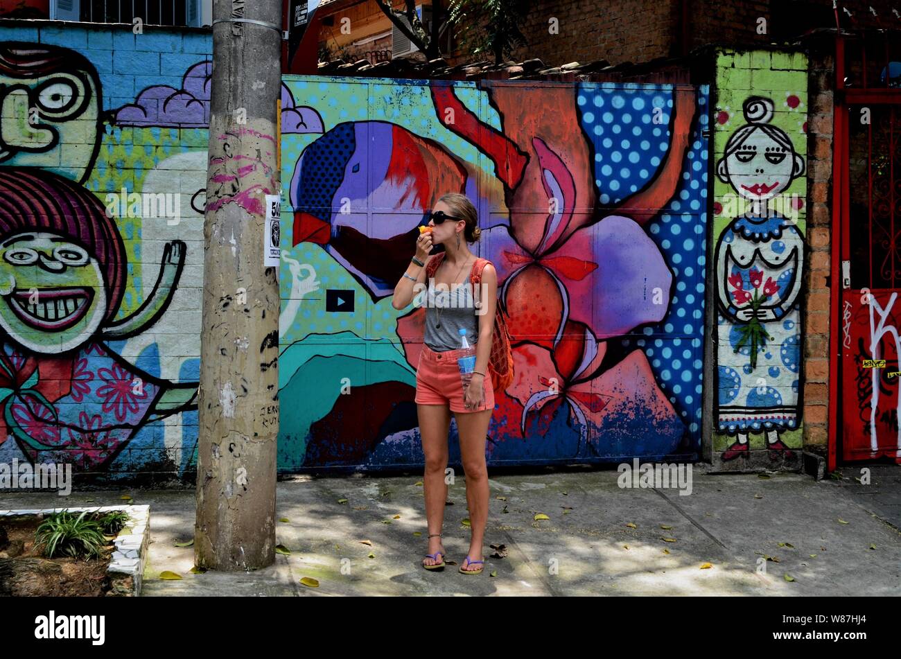 Ragazza di mangiare un frutto nella parte anteriore delle pareti di graffiti per le strade di São Paulo del Brasile nel 2013. Foto Stock