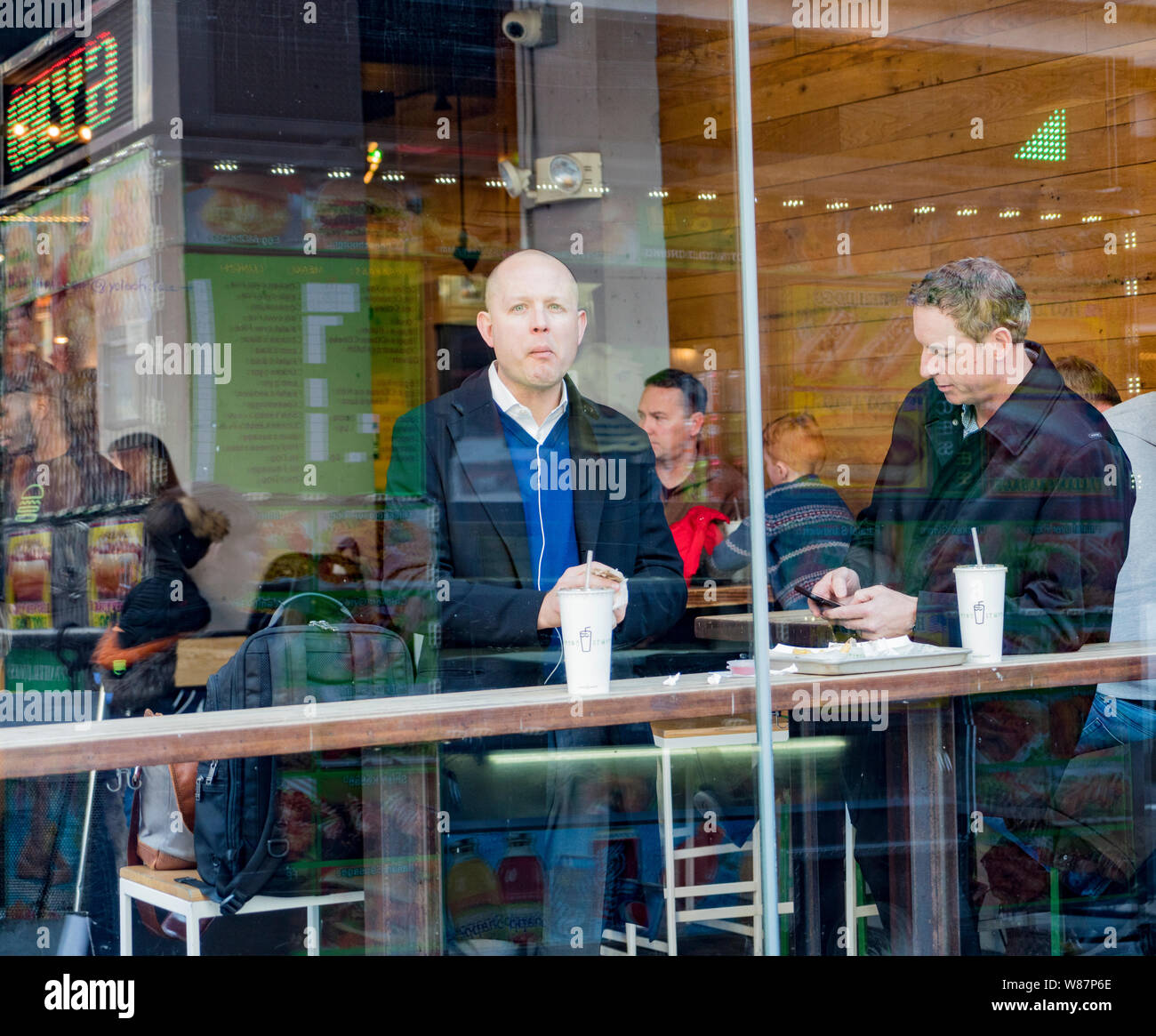 New York, Feb 14, 2018 - Persone di mangiare al bar al coperto visibile attraverso la finestra di street Foto Stock