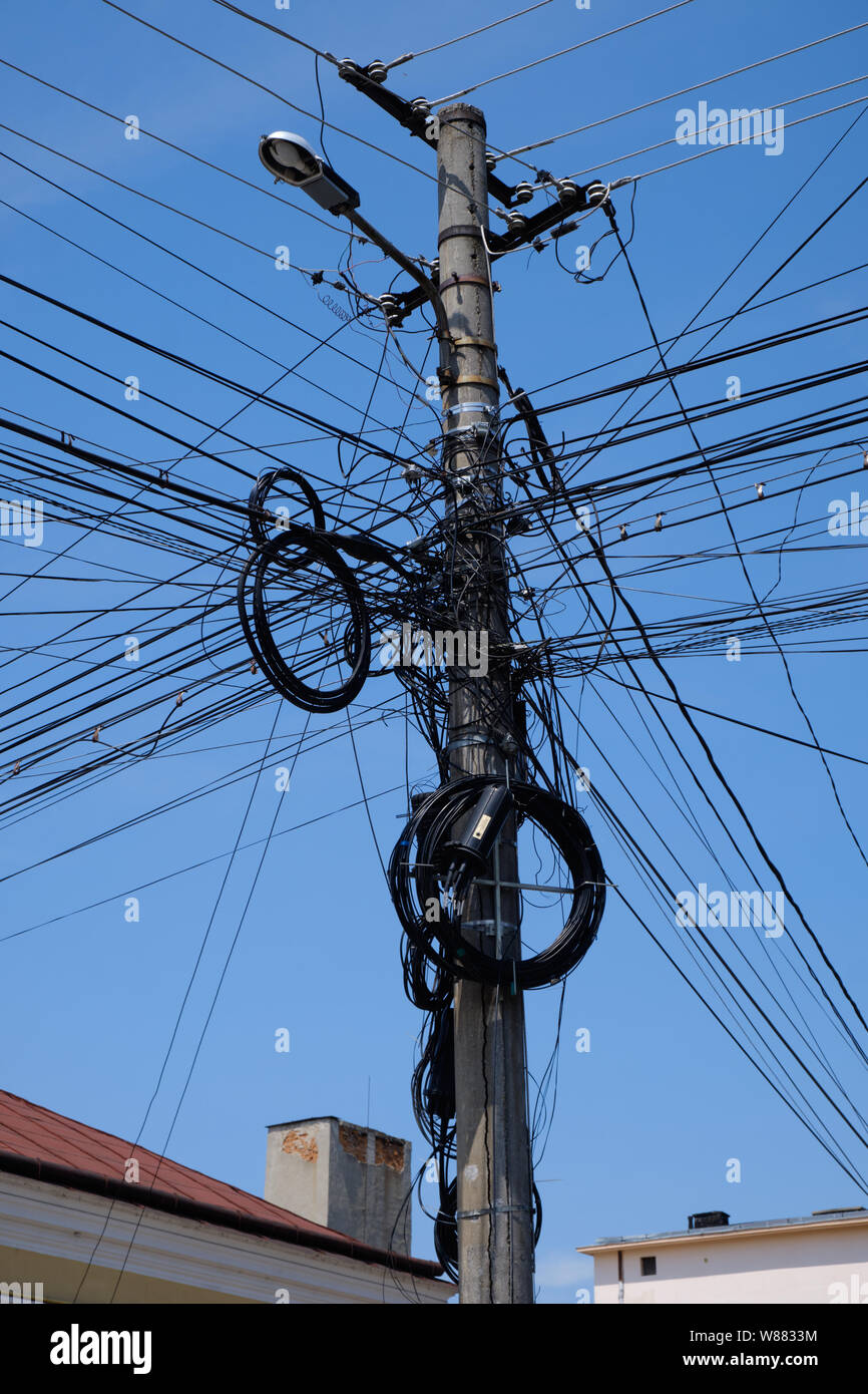 Affogate i fili elettrici in pole contro il cielo blu. Complessa rete di sopra di terra in Romania Foto Stock