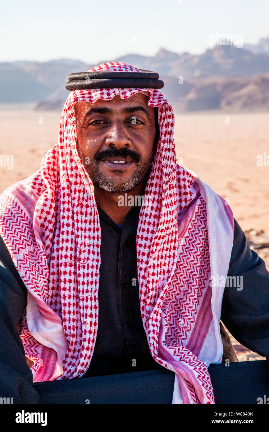 Un beduino uomo si siede sullo sfondo del deserto giordano a Wadi Rum o a valle della luna Foto Stock