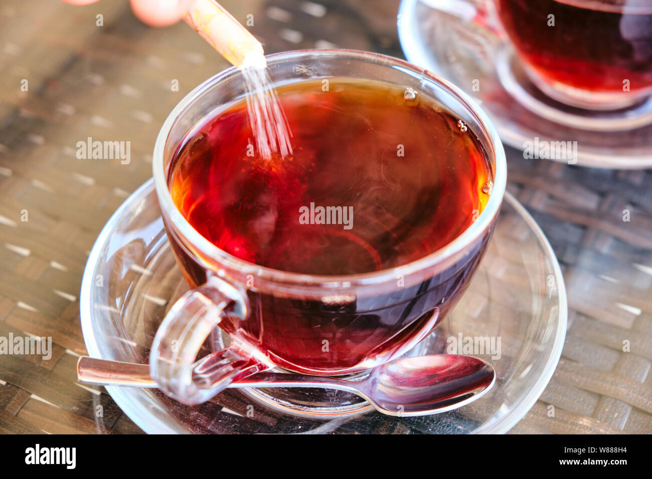 Lo zucchero si versa in un tradizionale tè turco in vetro Foto Stock