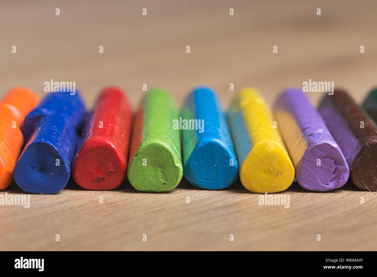 Diverse colorate le matite utilizzate in una fila su un sfondo di legno Foto Stock