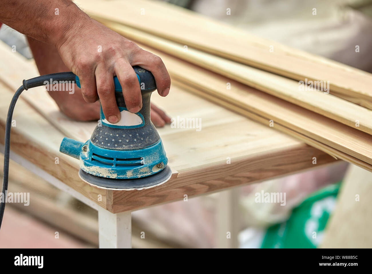 Macinacaffè lavoratore lucidi di una tavola di legno. Schede di levigatura orbitale macchina eccentrico. Foto Stock