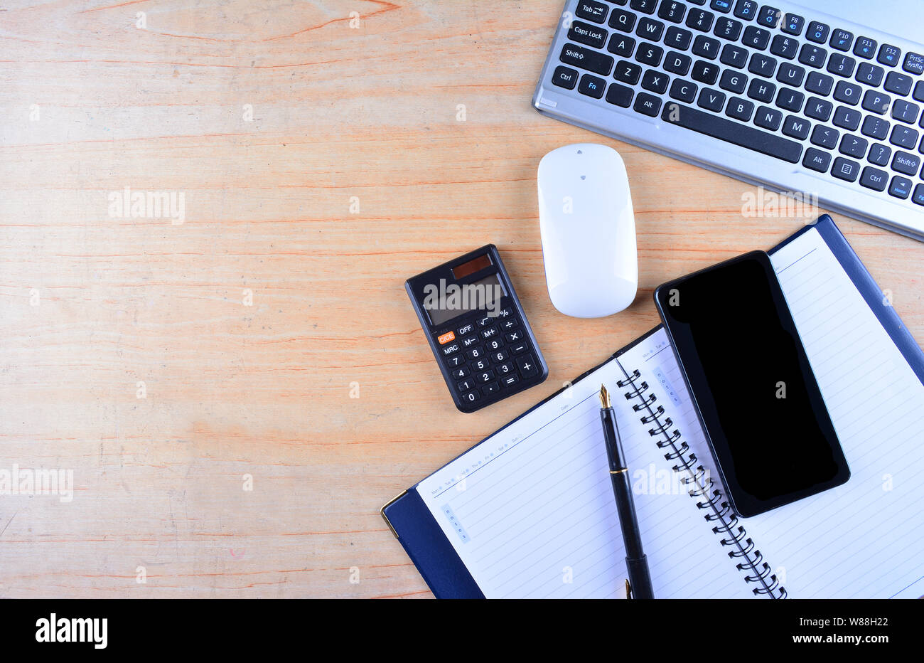 Tastiera e mouse, penna stilografica, notebook, calcolatrice e smartphone su un tavolo Foto Stock