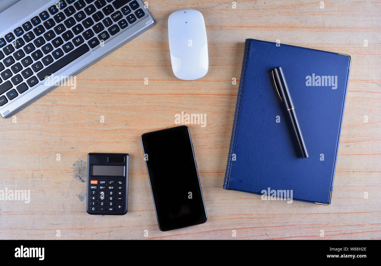 Tastiera e mouse, penna stilografica, notebook, calcolatrice e smartphone su un tavolo Foto Stock