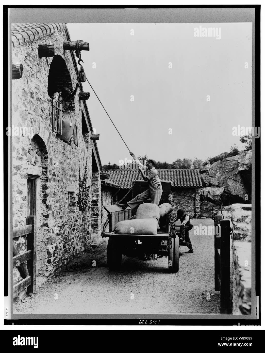 Sorpresa Valley Farm, Arthur Curtiss James proprietà, Beacon Hill Road, Newport, Rhode Island. Gli uomini il caricamento dei sacchi di granella dal carrello in cortile in secondo piano la porta della stalla Foto Stock