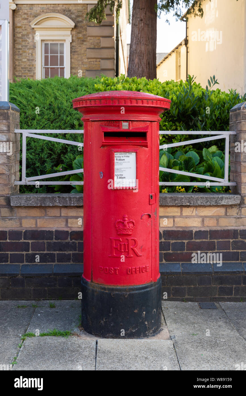 Market Harborough, Leicestershire, Regno Unito: Rosso Post Office ghisa Elizabeth II Post Office pilastro casella su un marciapiede con un basso muro e ringhiera dietro. Foto Stock