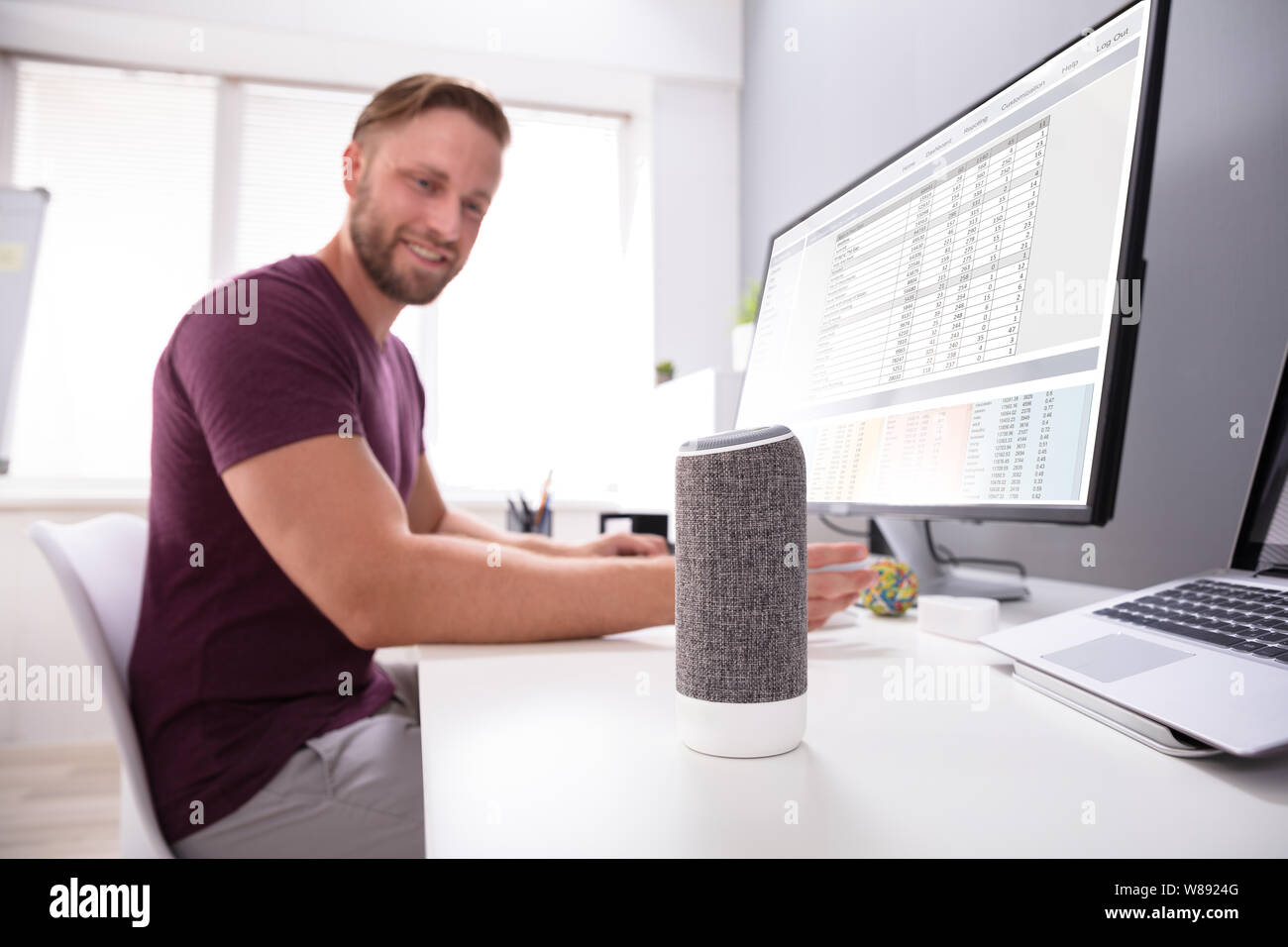 Imprenditore sorridente utilizzando Assistente vocale in ufficio Foto Stock