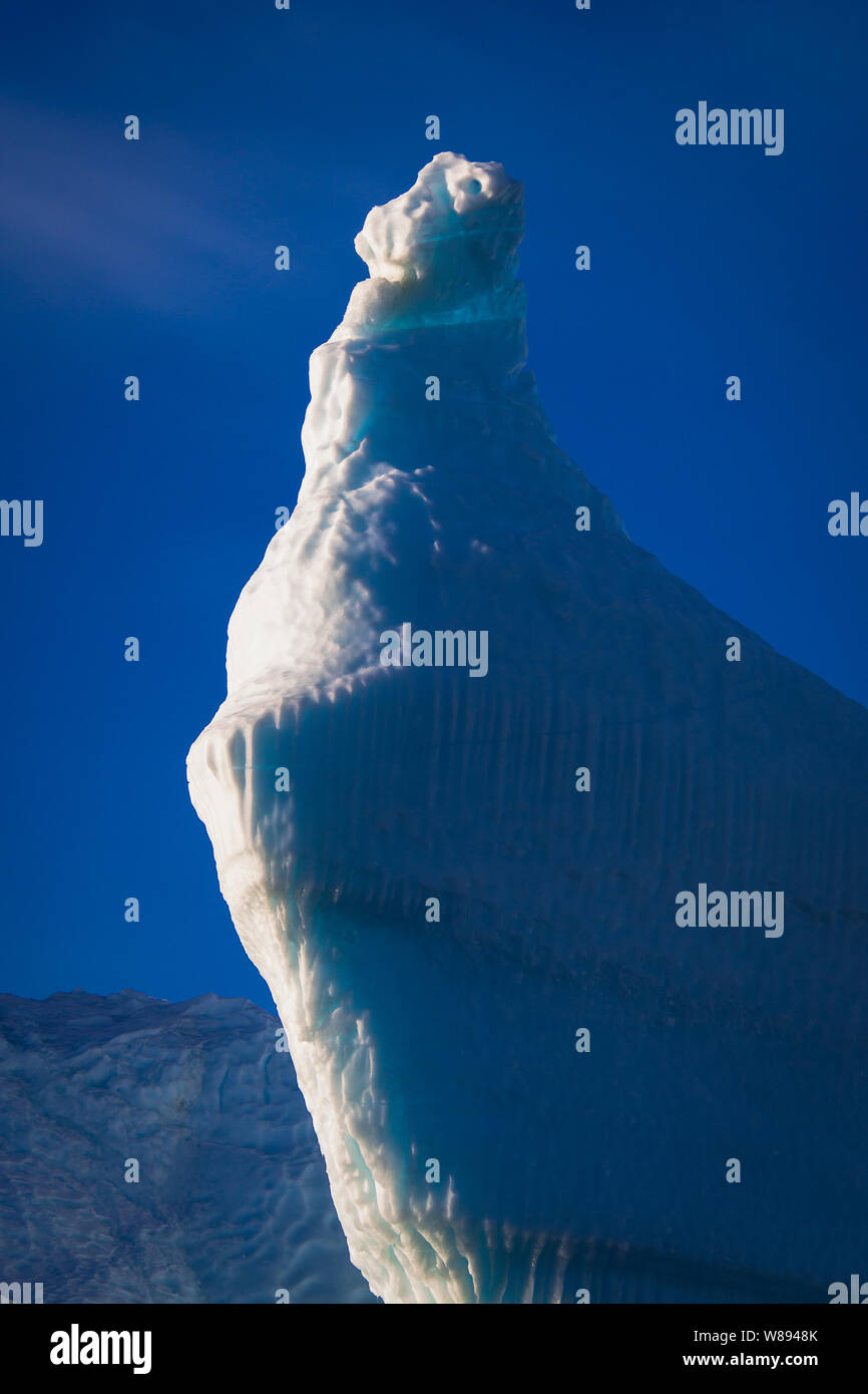 La parte superiore di un enorme a forma di rompighiaccio iceberg si illumina come una torcia come la luce del sole lo colpisce, nella parte orientale della Groenlandia Foto Stock