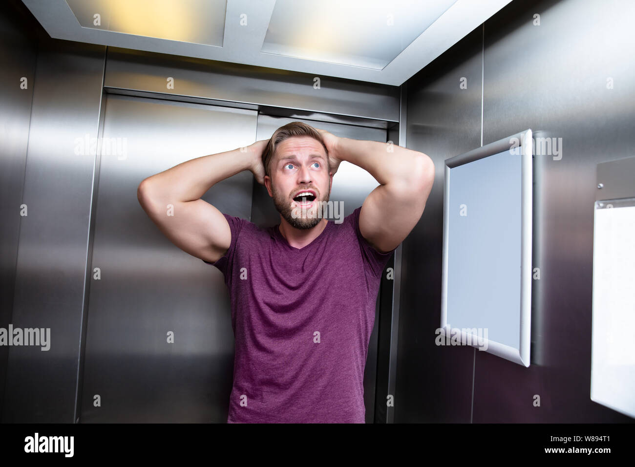 L uomo che soffre di claustrofobia intrappolato all'interno di ascensore urlando Foto Stock