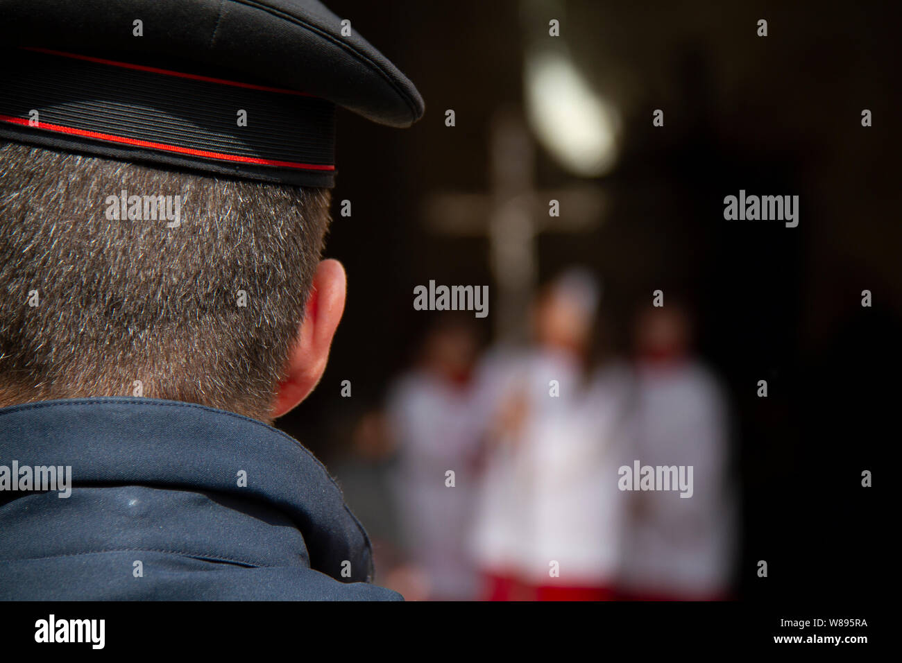 Un carabiniere funzionario di polizia orologi come processione del Venerdì santo emerge dalla Chiesa, guidata da un altare ragazza con un crocifisso in argento. Erice Sicilia Italia Foto Stock