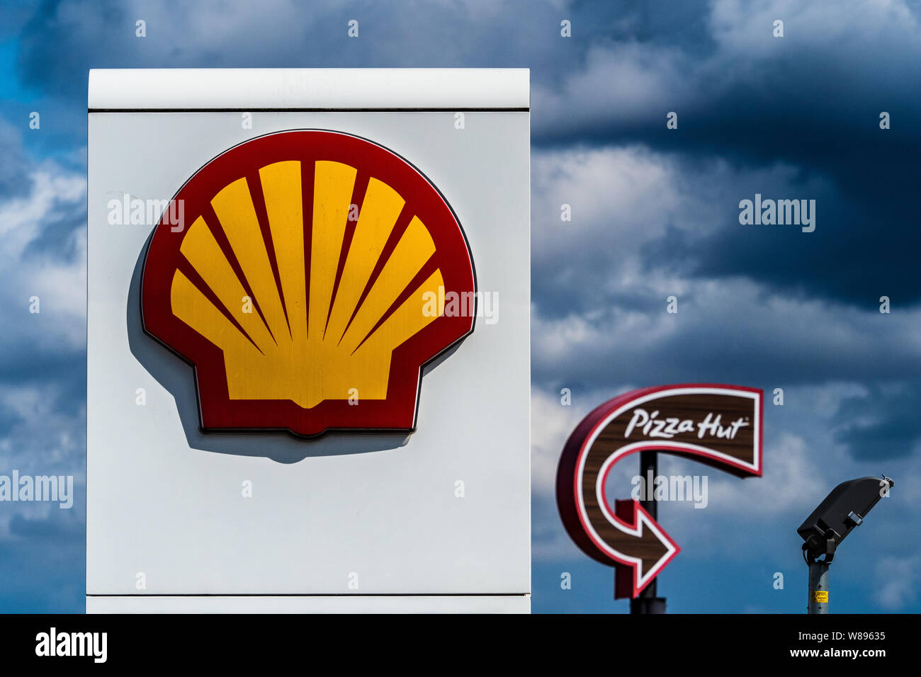 Il logo aziendale di Londra - Shell e Pizza Hut loghi contro un cielo tempestoso nel Central London REGNO UNITO Foto Stock