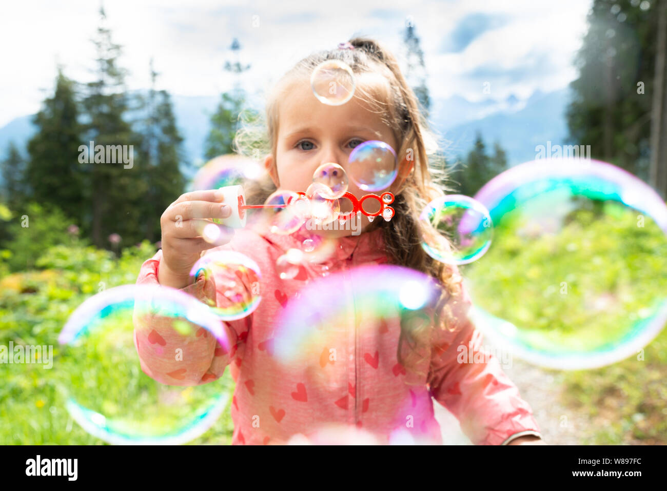Ragazza a soffiare bolle in una giornata di sole nel parco Foto Stock