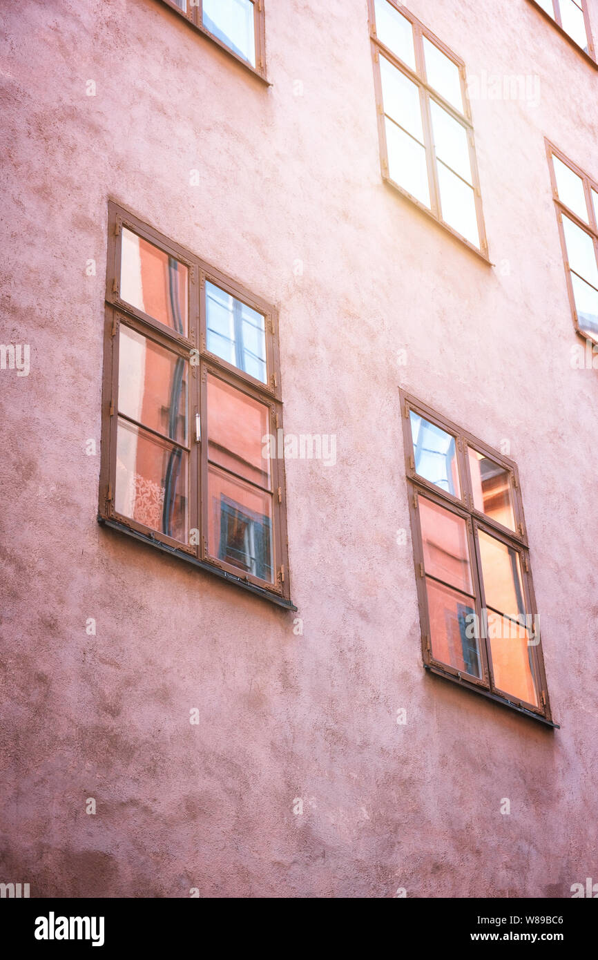 Parte della facciata di un rosso edificio storico illuminato, riflette i riquadri della finestra, nella vecchia città di Gamla Stan di Stoccolma, Svezia. Serie - stre Foto Stock