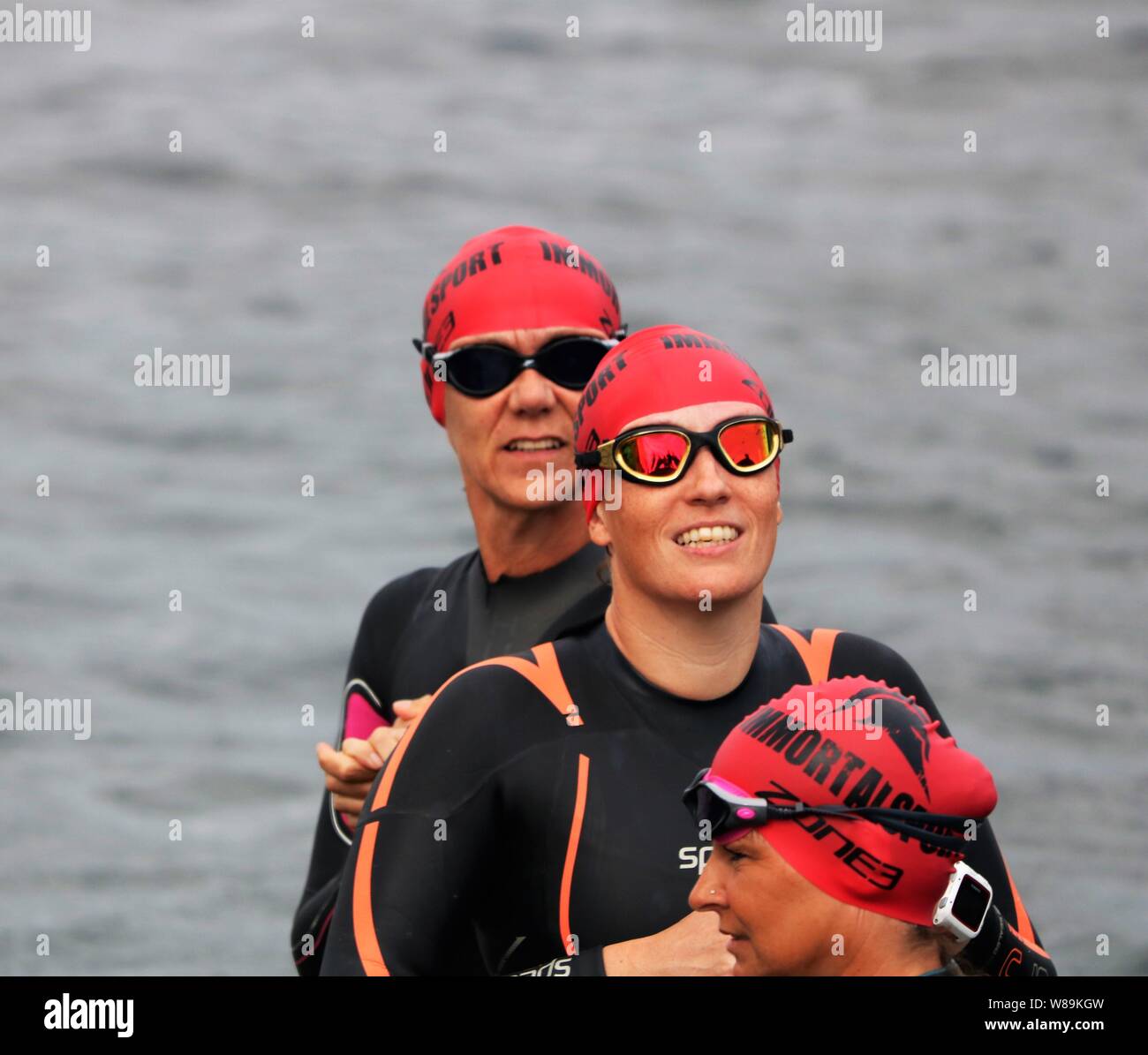 Le persone che hanno preso parte alla volata Farmoor Decathlon, iniziando con l'evento di nuoto, indossando cappelli di nuoto e mute. Foto Stock
