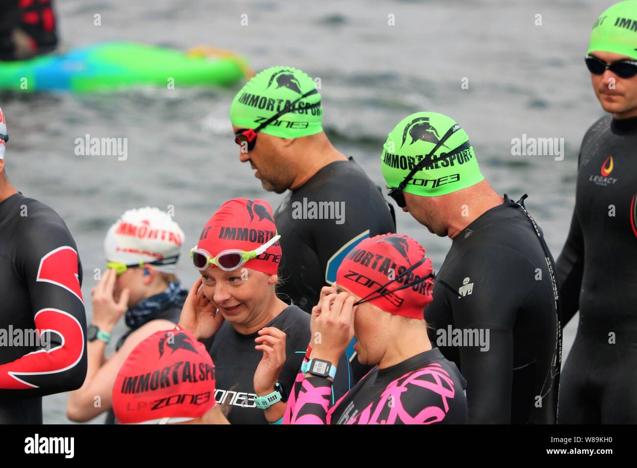 Le persone che hanno preso parte alla volata Farmoor Decathlon, iniziando con l'evento di nuoto, indossando cappelli di nuoto e mute. Foto Stock