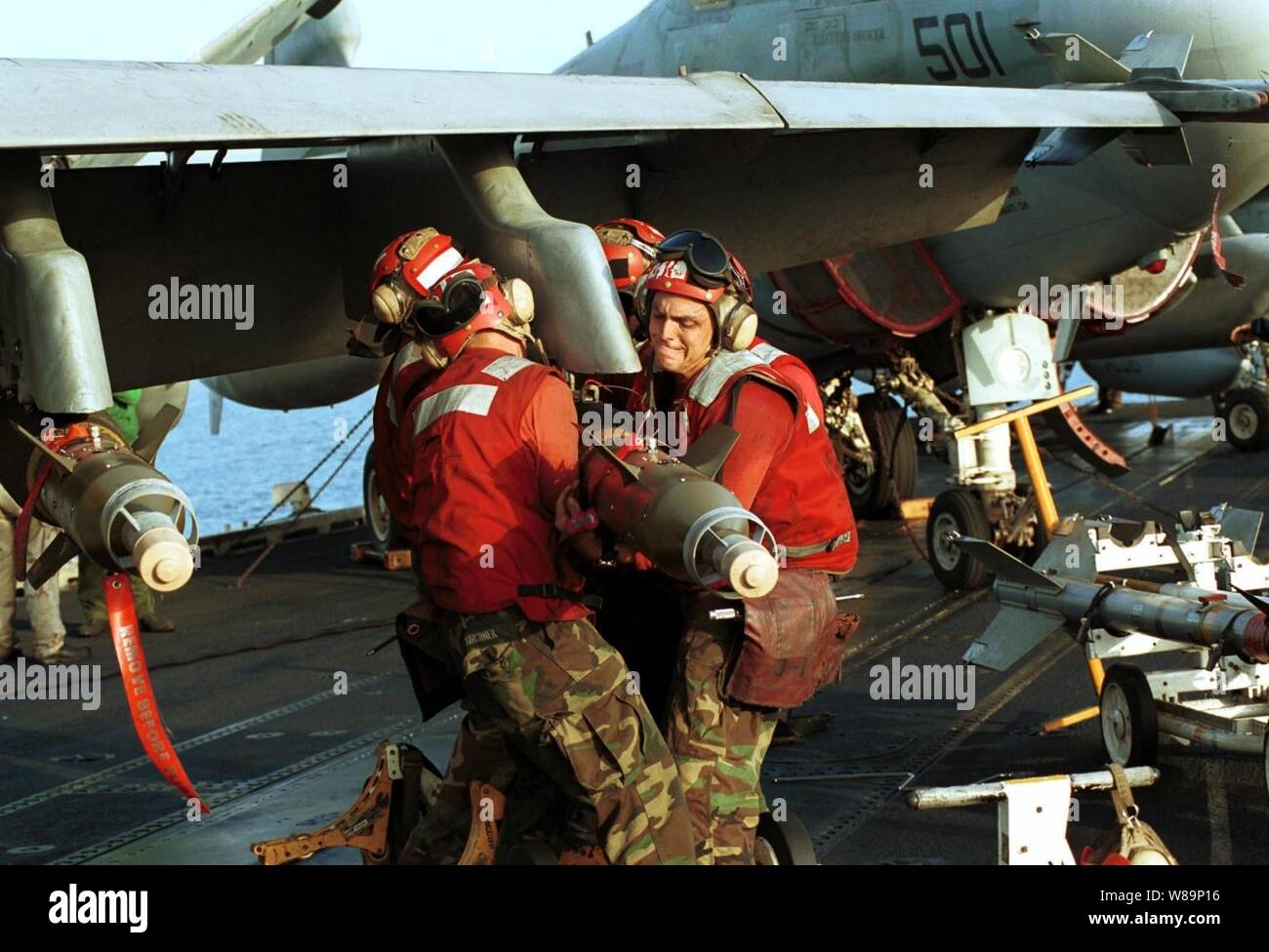Aviation ordnancemen sulla USS Enterprise (CVN 65) muscolo inesplosi nel luogo come aerei sono pronti per colpire le missioni contro al Qaeda terroristici dei campi di addestramento e installazioni militari del regime dei talebani in Afghanistan il 7 ottobre 2001, durante l'Operazione Enduring Freedom. La attentamente le azioni mirate sono state progettate per interrompere l'uso dell'Afghanistan come una base per azioni terroristiche e di attaccare le capacità militari del regime dei talebani. Foto Stock